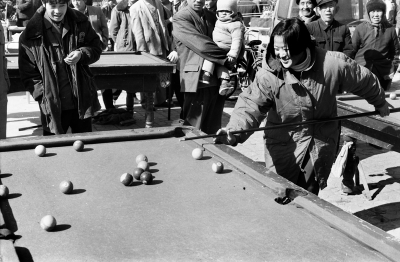 18《城鄉臺球熱》1996年,在濱州惠民的街頭,一位20歲左右的女孩在認真地打臺球。在上世紀八九十年代,隨著市場經濟大潮的興起,城鄉居民的娛樂項目日增,臺球老少皆宜,桌案一擺就打起來。(田軍).jpg